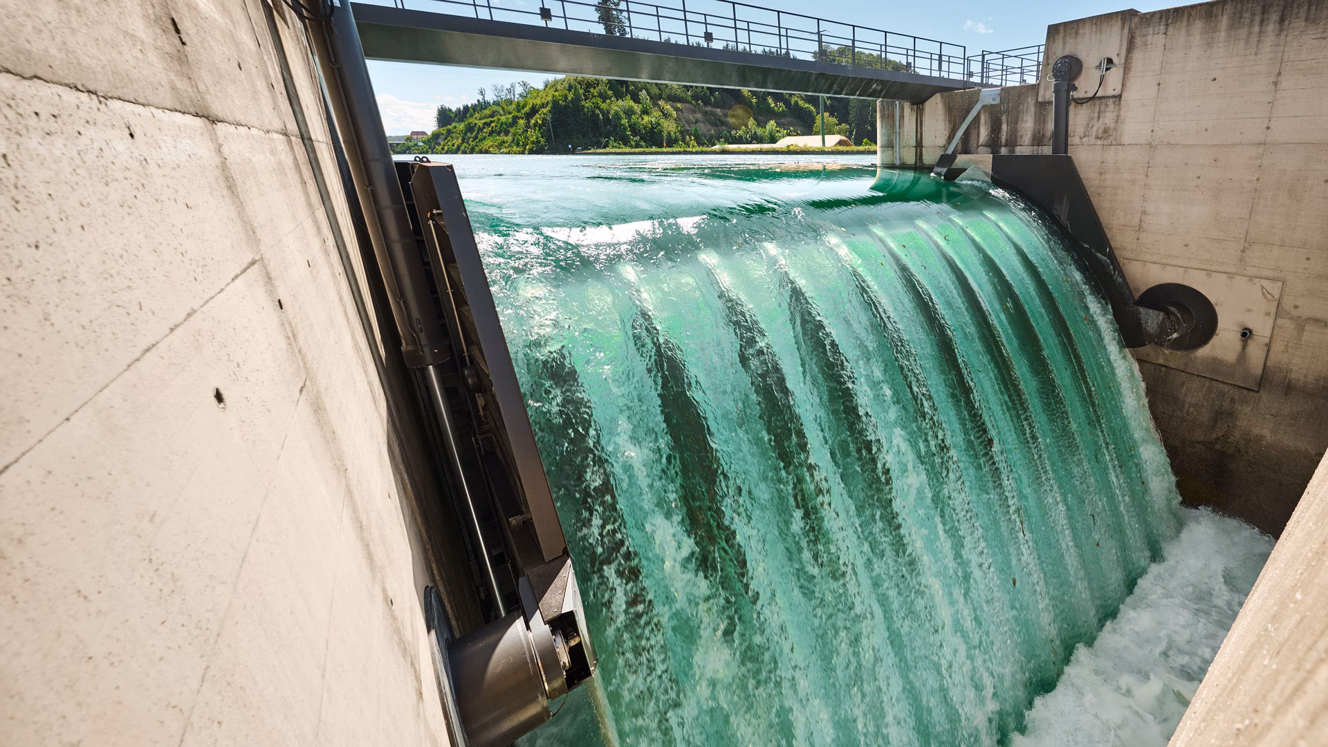 L'acqua scorre sopra una traversa tra pareti di cemento.
