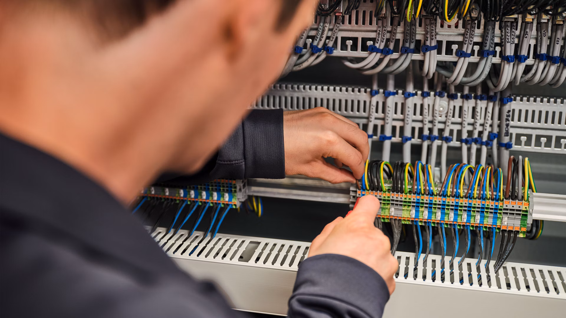 Techniker arbeitet an der Verkabelung in einem Schaltschrank.