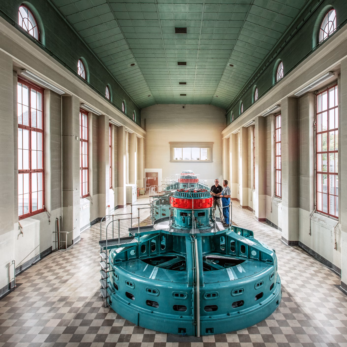 Sala turbine con macchina color turchese e alte finestre in un edificio industriale storico