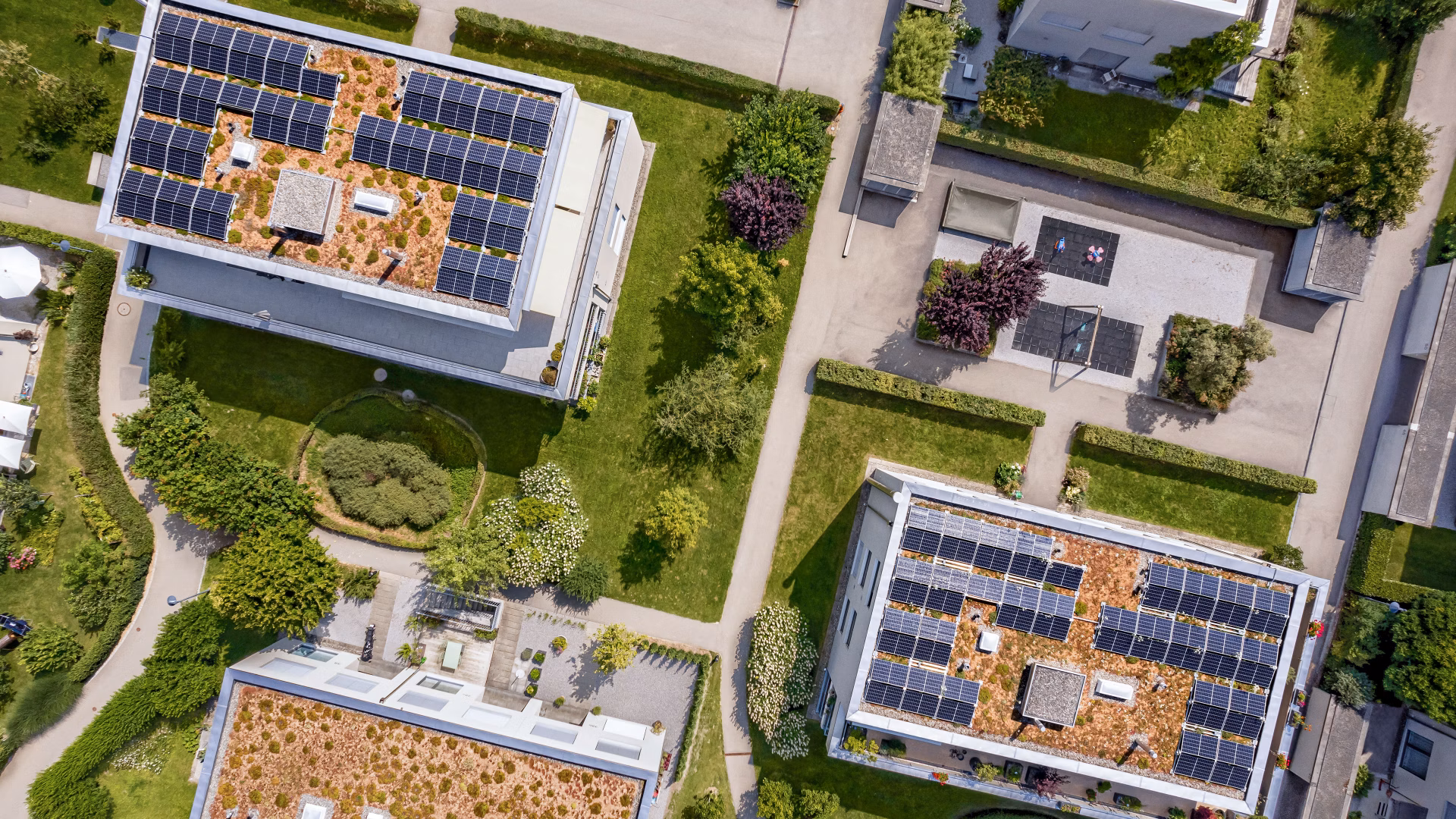 Drohnenansicht von Gebäuden mit Solaranlagen auf Flachdächern und begrünten Aussenbereichen