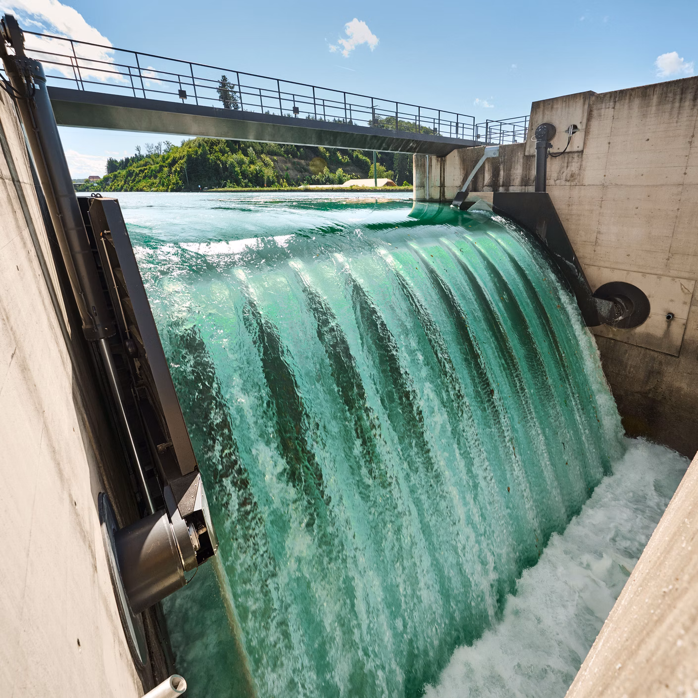 L'acqua scorre sopra una traversa tra pareti di cemento.