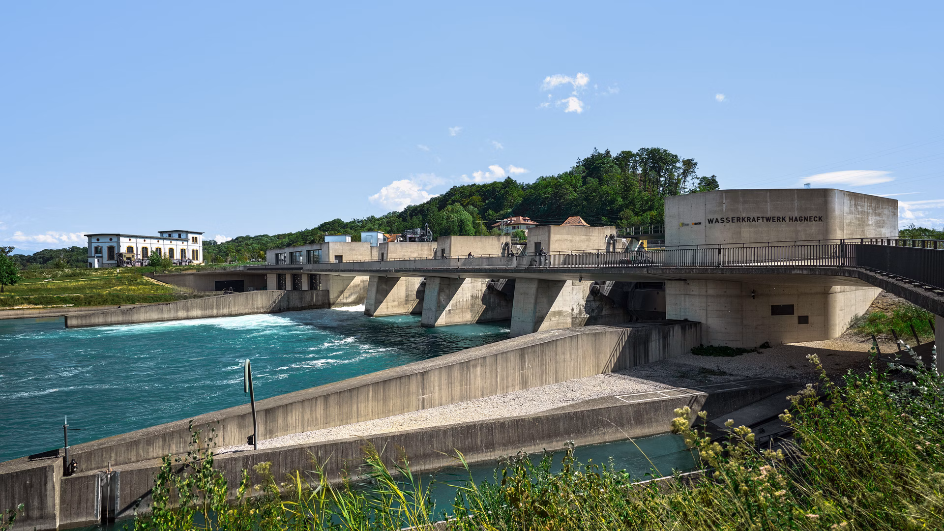 Wasserkraftwerk mit Wehr an einem Fluss bei klarem Himmel