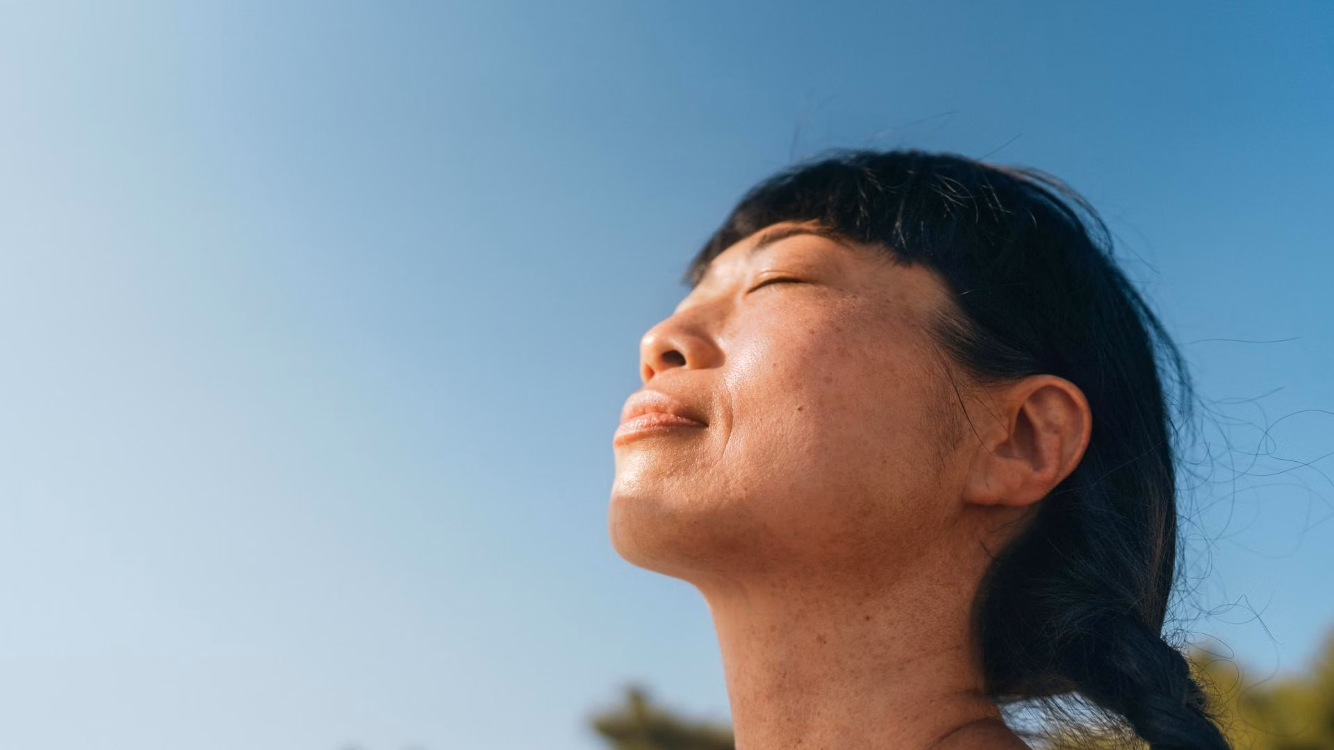 Frau mit geschlossenen Augen im Freien vor blauem Himmel