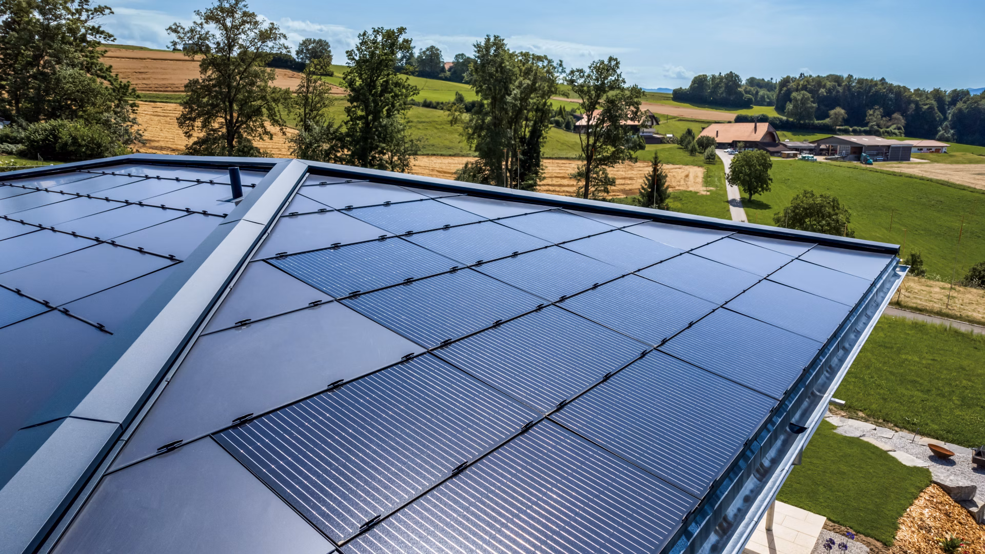 Photovoltaikanlage auf einem Gebäudedach mit Blick auf die ländliche Umgebung.