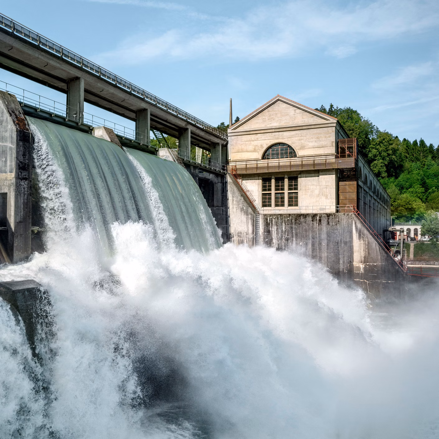 Centrale idroelettrica con forte deflusso d’acqua attraverso una diga accanto a un edificio operativo.