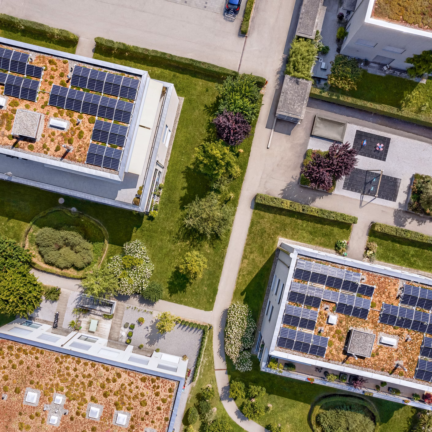 Drohnenansicht von Gebäuden mit Solaranlagen auf Flachdächern und begrünten Aussenbereichen