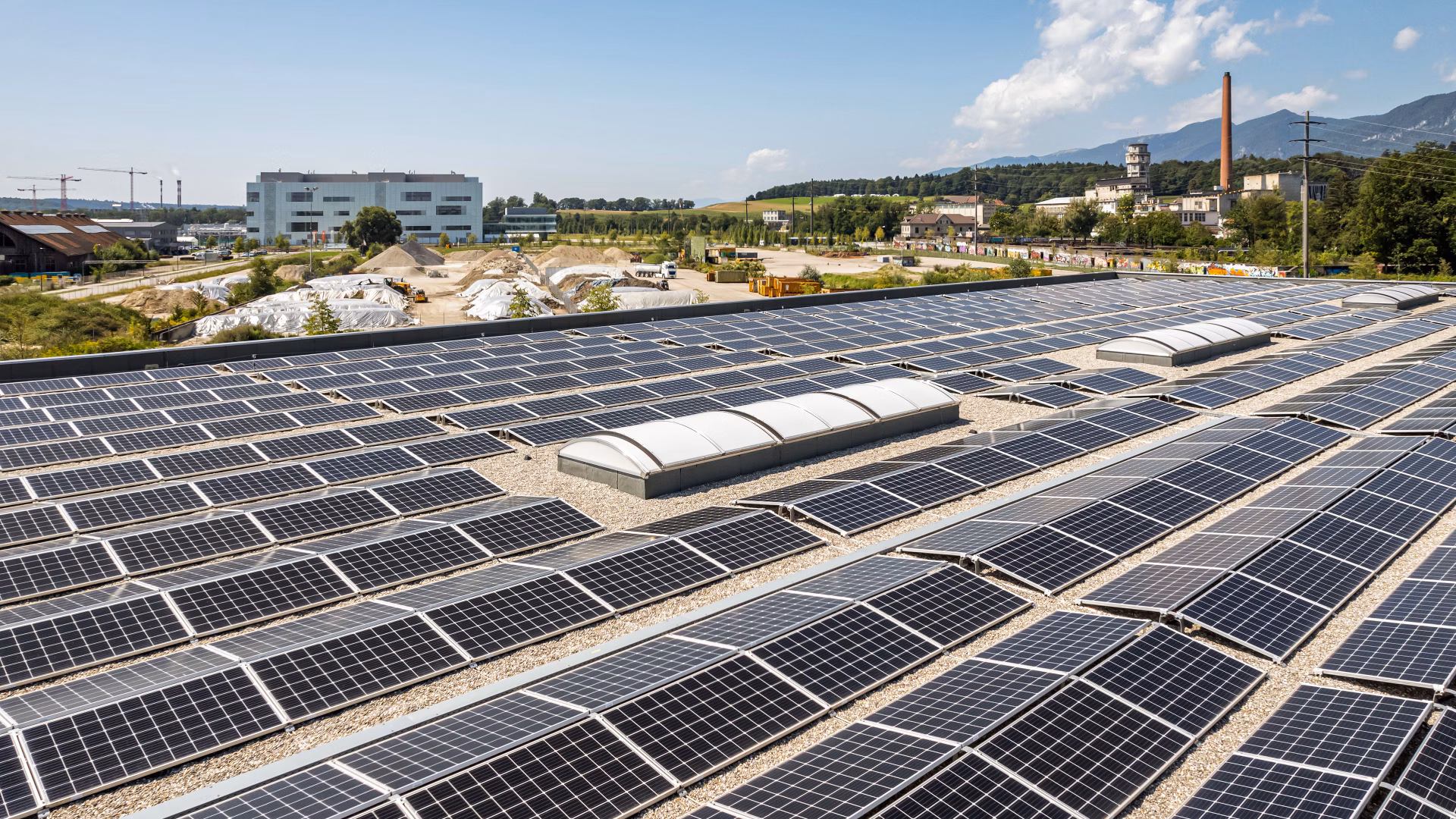 Solaranlage mit vielen Photovoltaikmodulen auf einem Flachdach in einem Industriegebiet